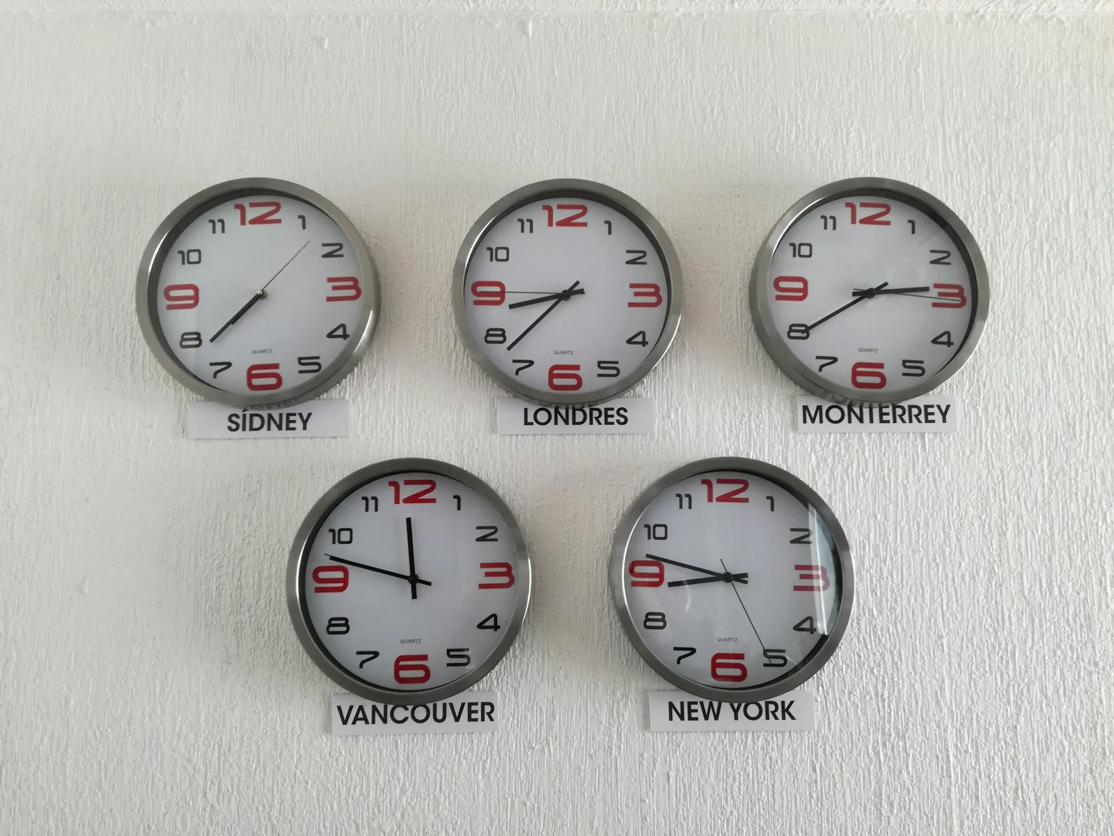 Wall clocks showing the time in Sydney, London, Monterrey, Vancouver and New York